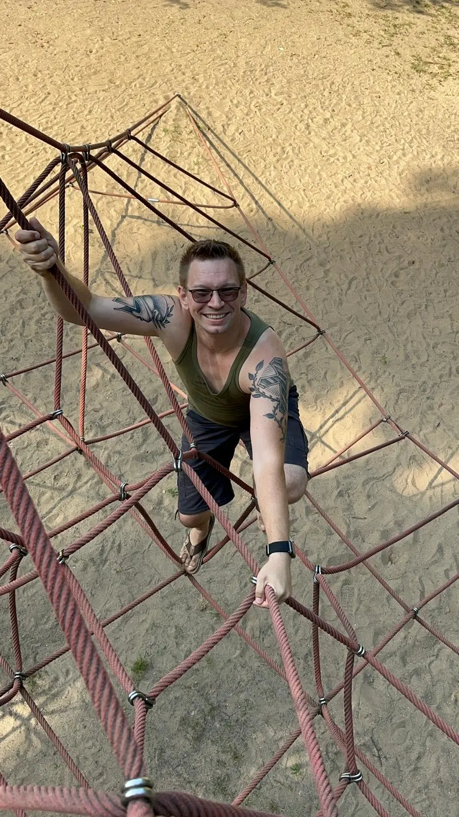 Beziehungscoach und Paarberater Martin Sosnowski klettert auf einem Spielplatz und lächelt den Fotografen an.